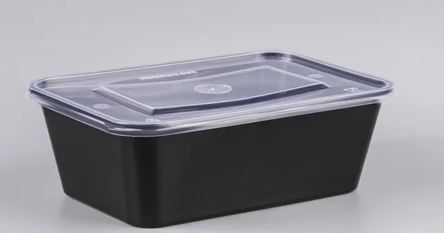 The clear lid of a black-based rectangular takeaway container, with the words Microwave safe moulded into its surface.